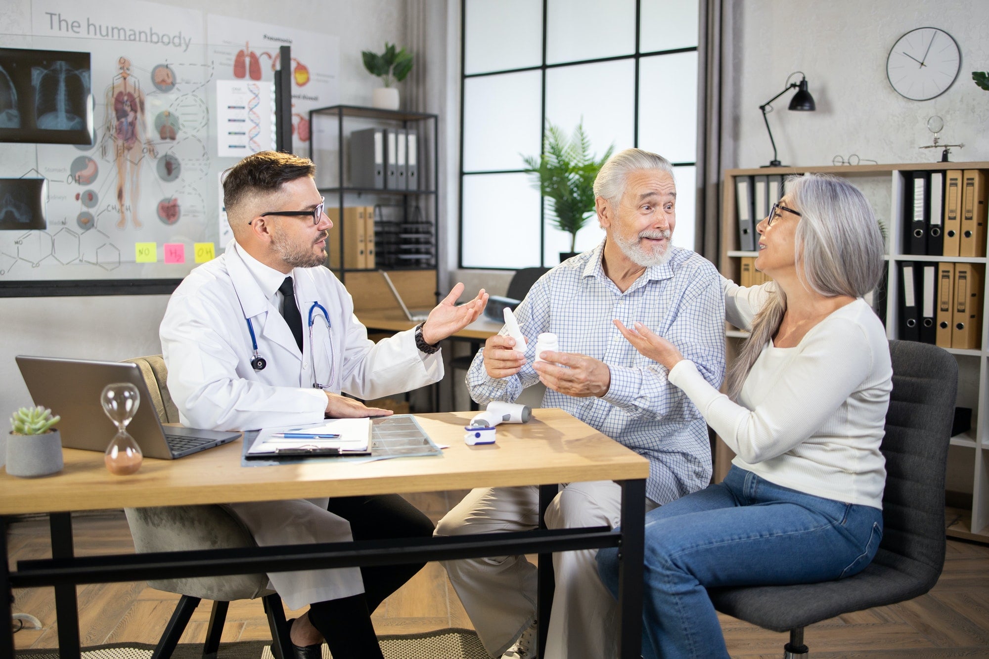 Excited in good mood aged couple getting medical consultation from family doctor